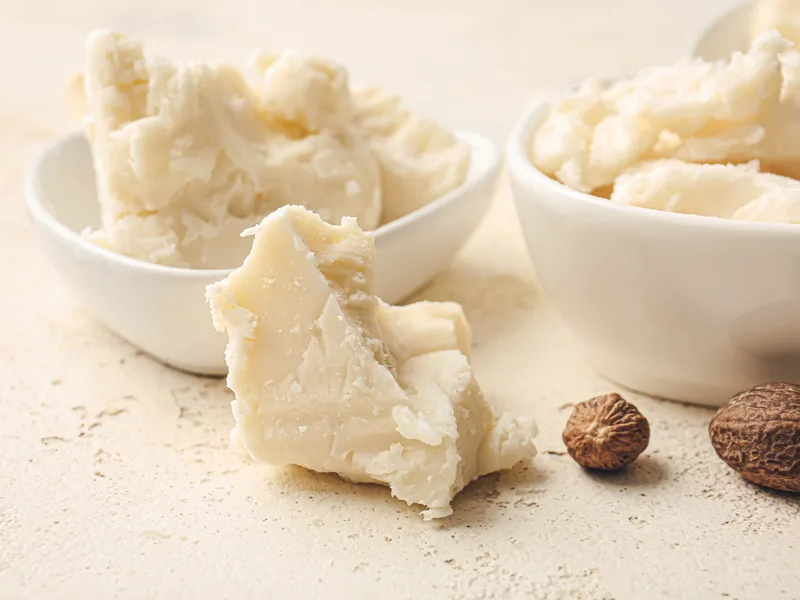 Raw shea butter in white bowls on a neutral background