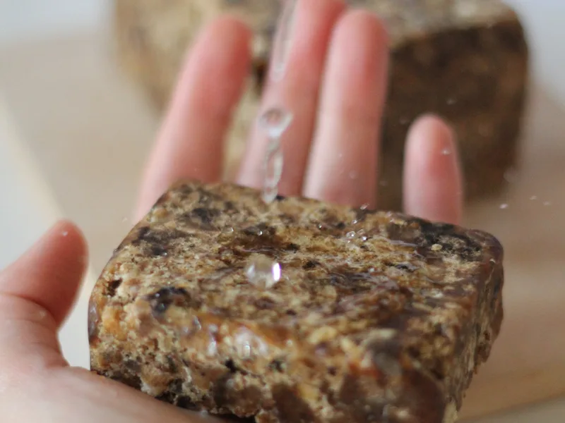 Hand holding a bar of African black soap